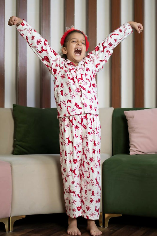  The set includes a long-sleeved top with a collar and matching pants, both adorned with delightful red prints of reindeer, snowflakes, and Christmas trees on a white background. 