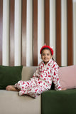  The set includes a long-sleeved top with a collar and matching pants, both adorned with delightful red prints of reindeer, snowflakes, and Christmas trees on a white background. 