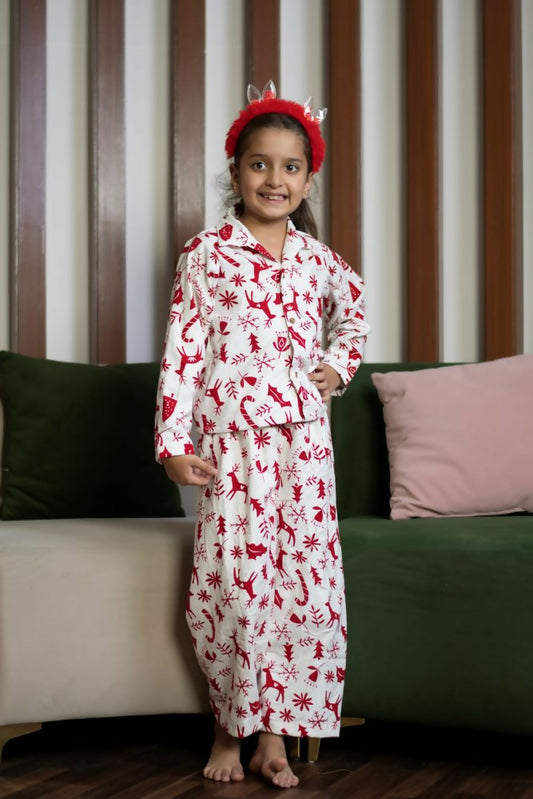  The set includes a long-sleeved top with a collar and matching pants, both adorned with delightful red prints of reindeer, snowflakes, and Christmas trees on a white background. 